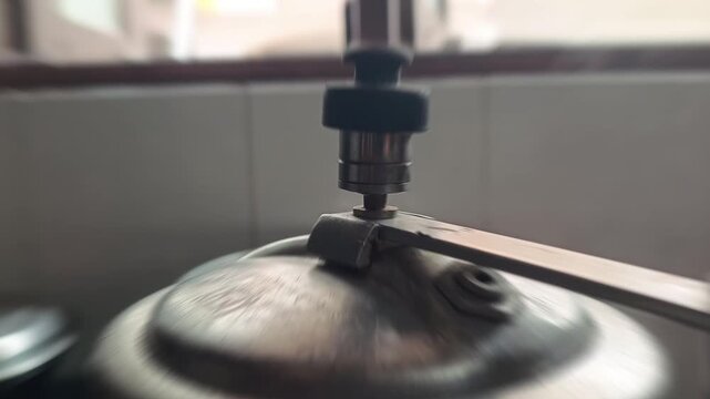 Close up of pressure cooker whistle releasing hot steam in kitchen