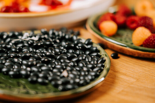 Black beans piled on a ceramic plate with fresh raspberries and apricots sitting on a wooden table
