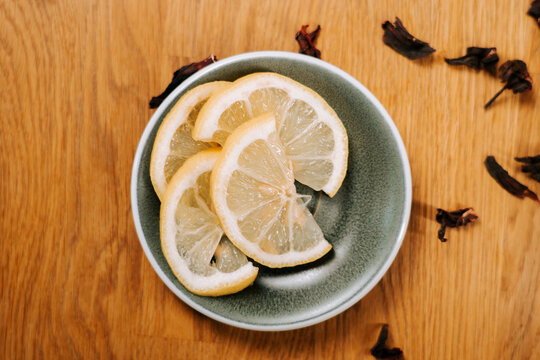 Yellow lemon slices in a green bowl on wood