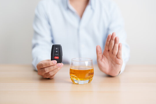 Responsible man reject a drink before driving for road safety, Man making stop hand gesture to refuse a glass of whiskey and car remote. Avoid drink and drive, Drunk Driving Law concept