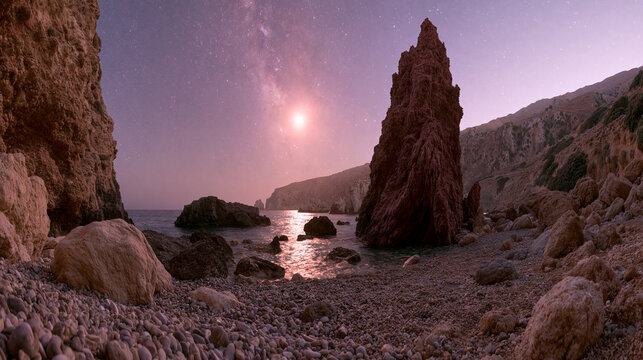 Milky way galaxy above rocky beach with tall sea stack formation at night, landscape