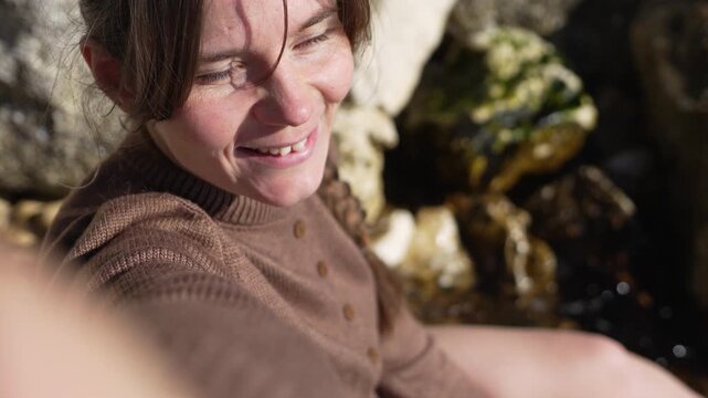 Smiling woman nature Happy young woman with a gap tooth grin enjoys a sunny day outdoors while filming a video among rocks