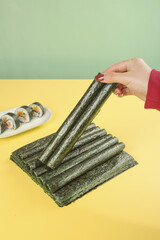 Woman hand picking nori seaweed sheets for homemade sushi preparation ready to eat healthy Japanese food © DinhThi