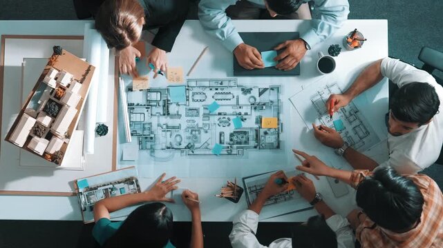 Top aerial view of project manager or civil engineer writing at blueprint and planning building design. Aerial view of architect working together at meeting table with document placed. Alimentation.
