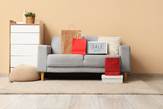 Online shopping sale on laptop screen with paper bags and boxes on a gray sofa in a Modern living room