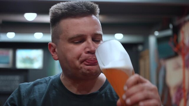 Young man holding a glass mug of light beer in a pub or bar. Close-up of a refreshing alcoholic drink with selective focus, social leisure, nightlife, relaxation and beverage concept.