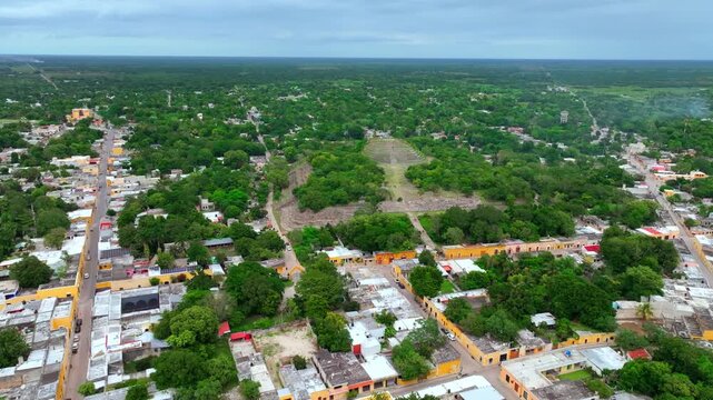 Aerial view over the green residential outskirts of Izamal, Yucatan, Mexico, scattered houses and garden plots spreading among tropical vegetation.