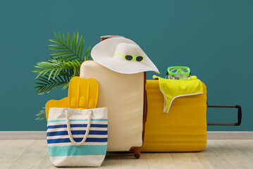 Summer vacation travel with packed suitcases, beach bag, hat, and snorkeling gear against a teal wall © Pixel-Shot