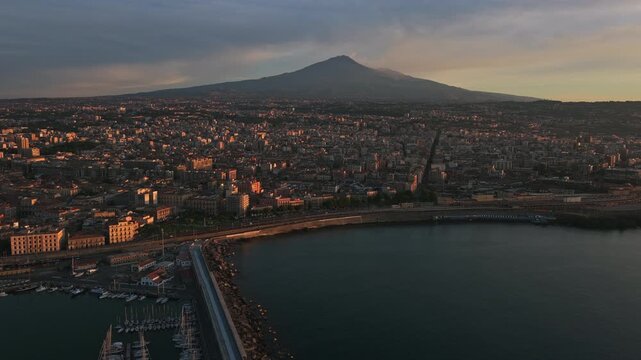 Catania City In Sicily, Italy, Overlooking The Gulf Of Catania, With Mount Etna Volcano In The Background At Dusk. - aerial shot