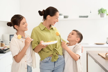 Young mother with her children and cottage cheese pancakes in kitchen