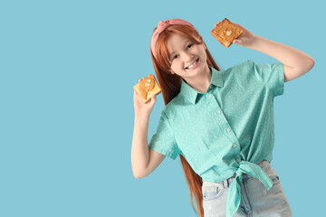 Teenage redhead girl holding toasts with nut butter on blue background