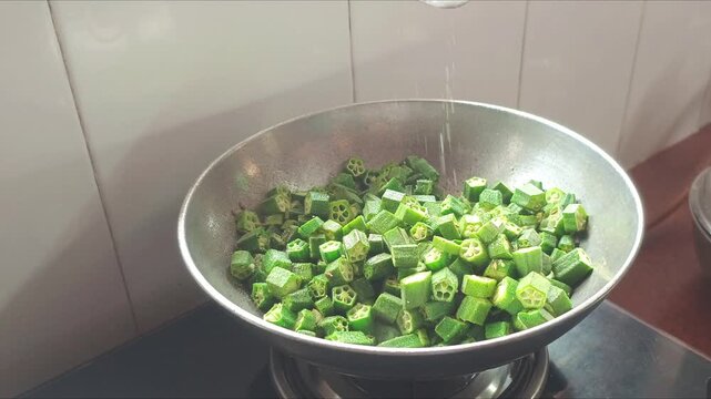 Chef Adding Salt and Turmeric Powder to Chopped Okra Ladyfinger Fry Cooking in Pan