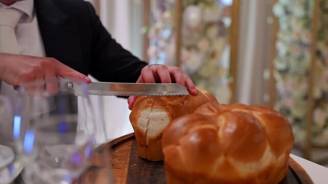 Close up view of Traditional Jewish wedding ceremony moment with challah bread being cut and served.