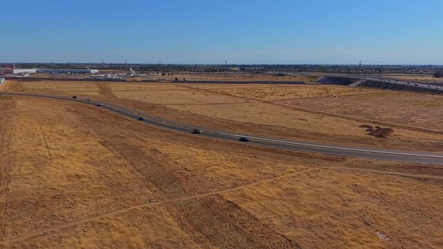 Reversing Arc Shot Aerial Drone Right to Left Over Dirt Field With Freeway Overpass Power Lines and Traffic in Fresno California