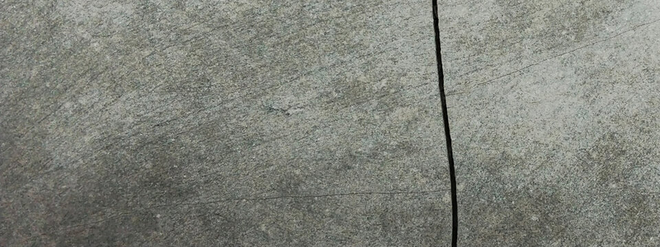 The concrete surface has developed vertical cracks.
