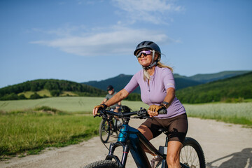 Obraz premium Active senior couple exploring nature on electric bicycles