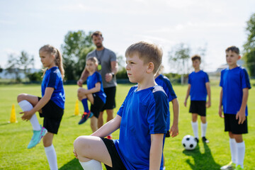 Naklejka premium Young football players warming up before training session on pitch.