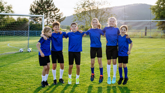 Mixed youth football team standing together on soccer field before training.