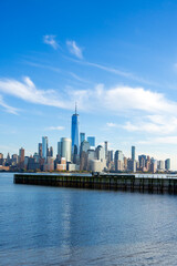 Obraz premium New York skyscrapers near waterfront. New York buildings form cityscape. New York City skyline with NYC. New York harbor and Lower Manhattan.