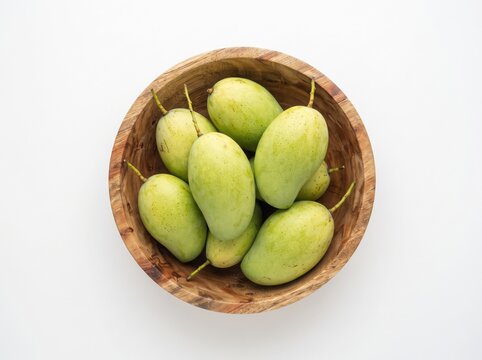 Fresh green mangoes in wooden bowl on white background high angle view.