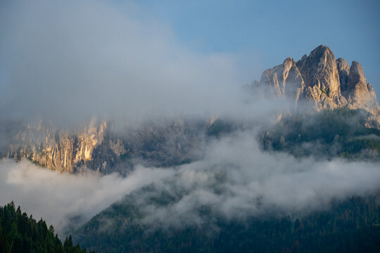 Aesthetic view of the Rosengarten mountain group rising above morning fog in the Dolomites, South Tyrol, Italy