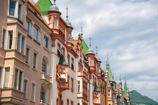 Elegant historic buildings with decorative facades, towers and green tiled roofs lining a street in the old town of Bolzano, South Tyrol, Italy