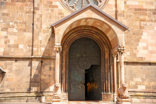 Decorated Gothic entrance of Bolzano Cathedral featuring bronze doors and traditional stone lion sculptures in the historic center of Bolzano, South Tyrol, Italy