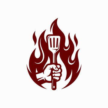 Hand holding a spatula surrounded by red flames.