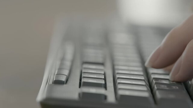A close-up of a woman's hands actively typing on a dark keyboard in a casual workspace setting.