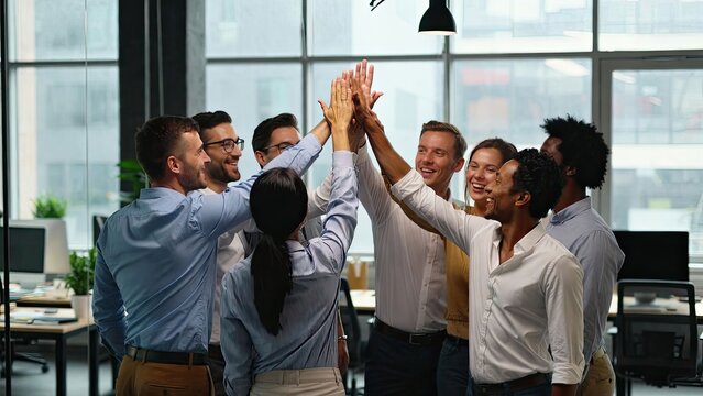 Team celebration in modern office colleagues high fiving after successful project completion