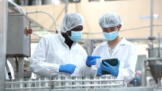 Quality assurance team checking seafood production line with clipboard inside food manufacturing plant. Food safety inspection, factory operations, production monitoring, quality management.