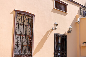 Obraz premium Peach Old Town Wall with Ornate Iron Window Grilles and Vintage Lanterns