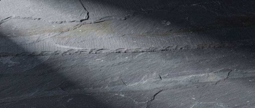 Dark grey slate stone texture background. Natural black rock surface with dramatic light.