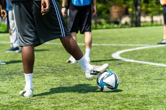 Close up feet of African male football player practicing with soccer ball. 