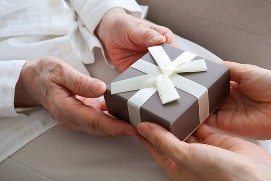Young Woman Giving a Gift Box to Senior Woman at Home
