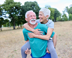 Obraz premium Smiling active senior couple having fun together in the park, active healthy elderly people bonding, older couple happy relationship