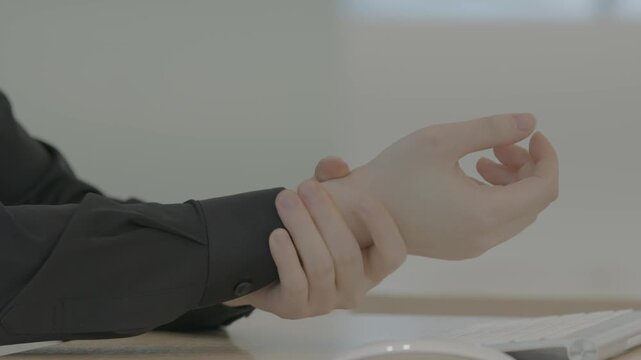 A close-up of a person holding their wrist in pain suggesting carpal tunnel syndrome or repetitive strain injury from computer use.