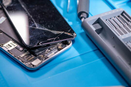 Smartphone technician repairing disassembled mobile phone hardware.
