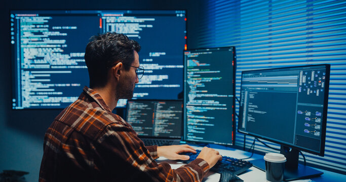 Young Caucasian male programmer write code on computer in home office at late night. AI technology, cybersecurity, software developer, freelance innovation, database system, digital network concept.