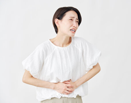 ミドルエイジ女性　腹痛　白背景