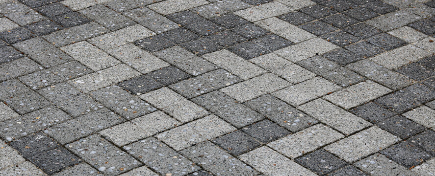 Detailed view of an outdoor pedestrian walkway constructed with speckled interlocking concrete paving stones.