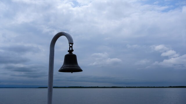 A ship's bell against a blue sky with clouds, a sea voyage.