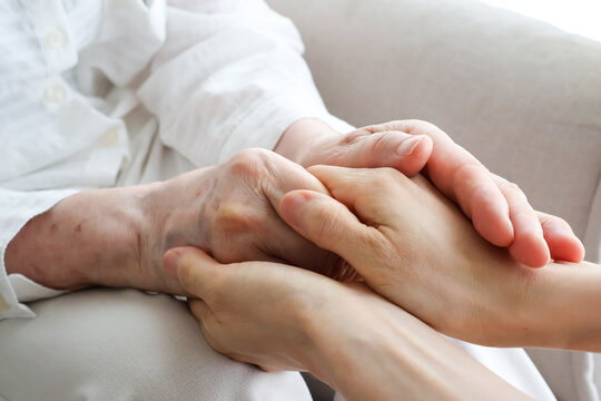 Young Caregiver Holding Senior Woman's Hands with Compassion at Home