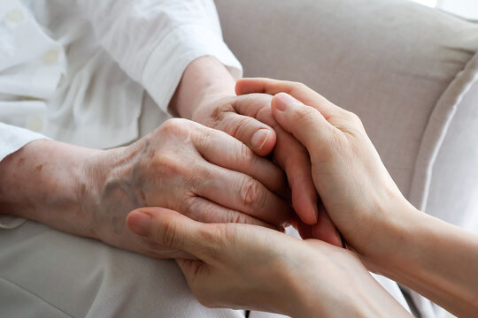 Young Caregiver Holding Senior Woman's Hands with Compassion at Home