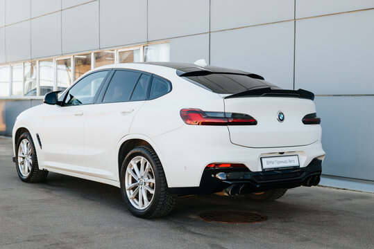 A BMW X4 stands parked next to a modern building with large windows. The vehicle is positioned to showcase its rear profile and sporty design during daylight Smolensk, Russia 07.17.2026