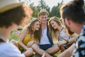 Fototapeta premium Group of young friends sitting on ground at summer festival.