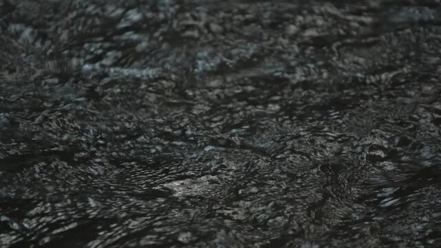 Dark water surface flowing gently with continuous ripples and small waves, featuring real relaxing river ambient sound audio.