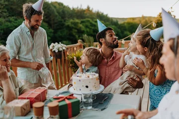 Multi generation family celebrating birthday on terrace. © Halfpoint