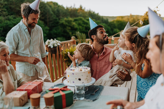 Multi generation family celebrating birthday on terrace.