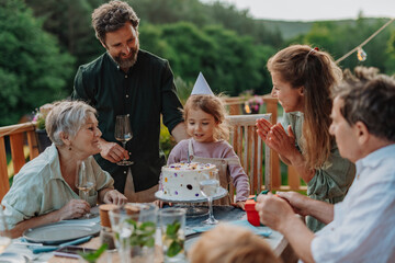 Fototapeta na wymiar Multi generation family grilling outside on patio in summer during garden party